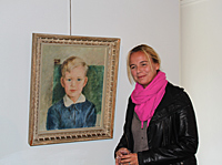 Cecilia Thaning in front of the portrait of her father Gunnar